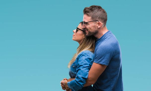 Young couple in love wearing sunglasses over isolated background looking to side, relax profile pose with natural face with confident smile. - Foto, Imagen