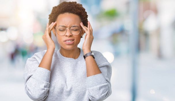 Young beautiful african american woman wearing glasses over isolated background with hand on head for pain in head because stress. Suffering migraine. - Zdjęcie, obraz
