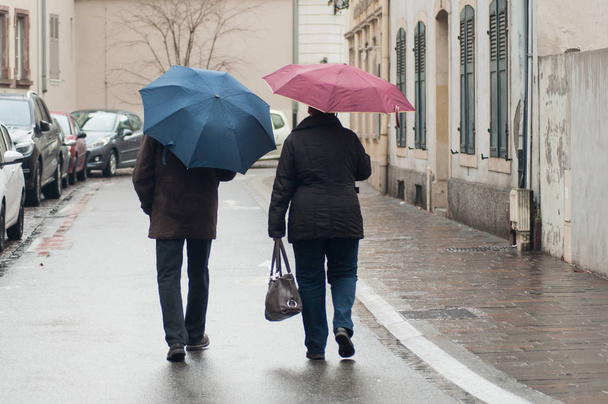 portrait of couple  walking with colorful umbrellas in the street on back view - Foto, Imagem