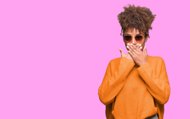 Beautiful young african american woman wearing sunglasses over isolated background shocked covering mouth with hands for mistake. Secret concept. - Φωτογραφία, εικόνα
