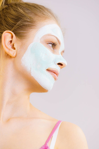 Mujer joven con máscara de barro verde blanco en la cara. Chica adolescente cuidando de la piel grasa, limpiando los poros. Tratamiento de belleza. Cáscara. - Foto, Imagen