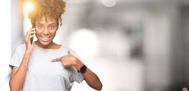 Genç Afro-Amerikan kadın Smartphone'da sürpriz yüz işaret parmağı kendini izole arka plan üzerinde söz - Fotoğraf, Görsel