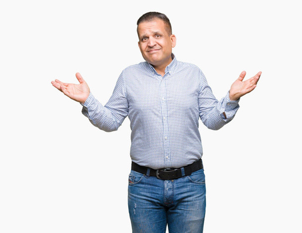 Арабський бізнесмен середнього віку над ізольованим тлом безглуздий і заплутаний вираз з піднятими руками і руками. Концепція сумніву
. - Фото, зображення