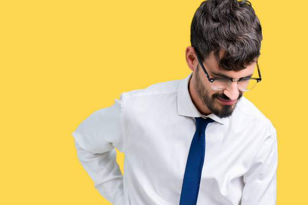 Jonge knappe business man dragen bril over geïsoleerde achtergrond lijden van rugpijn, aanraken terug met hand, spierpijn - Foto, afbeelding