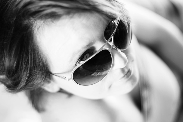 Fashion portrait of a beautiful young woman wearing sunglasses - 写真・画像