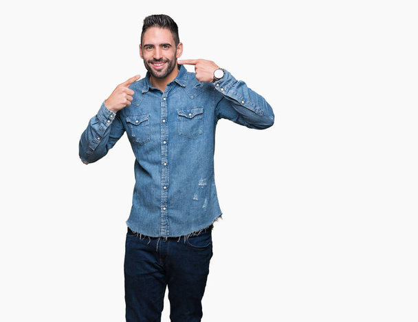 Young handsome man over isolated background smiling confident showing and pointing with fingers teeth and mouth. Health concept. - Фото, изображение