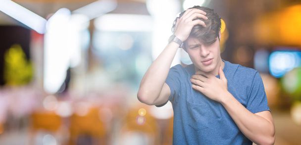 Mladý pohledný muž nosí modré tričko nad izolované pozadí dotýká čela nemocí a horečka, chřipka a nachlazení, virus nemocné - Fotografie, Obrázek