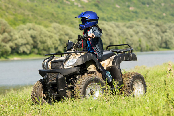 The boy is traveling on an ATV. - Foto, afbeelding