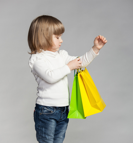 Little girl holding multicolored shopping bags - Fotoğraf, Görsel