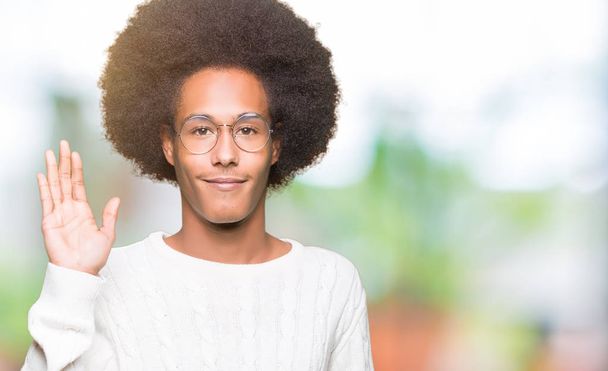junger afrikanisch-amerikanischer Mann mit Afro-Haaren und Brille, der auf ein fröhliches Hallo und eine freundliche Willkommensgeste verzichtet - Foto, Bild
