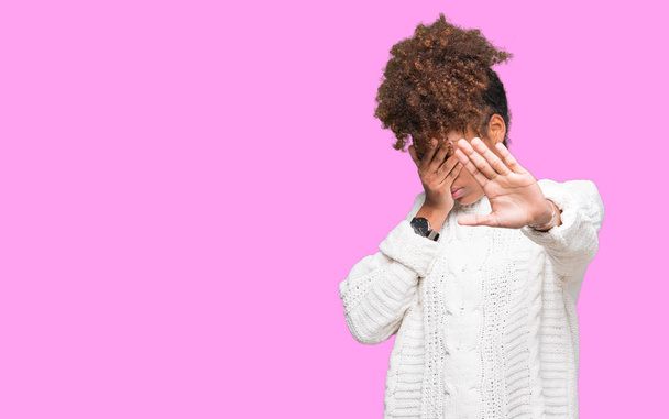 Mooie jonge african american vrouw winter trui dragen over geïsoleerd achtergrond die betrekking hebben op ogen met handen en stop doen gebaar met verdrietig en bang expressie. Beschaamd en negatieve concept. - Foto, afbeelding