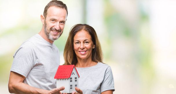 Middle age hispanic casual couple buying new house over isolated background with a happy face standing and smiling with a confident smile showing teeth - Fotó, kép