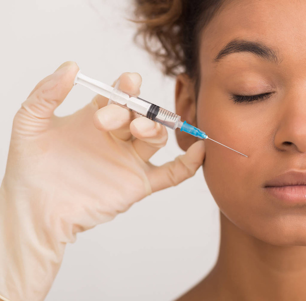 African-american woman getting face injection in clinic - Foto, Imagen