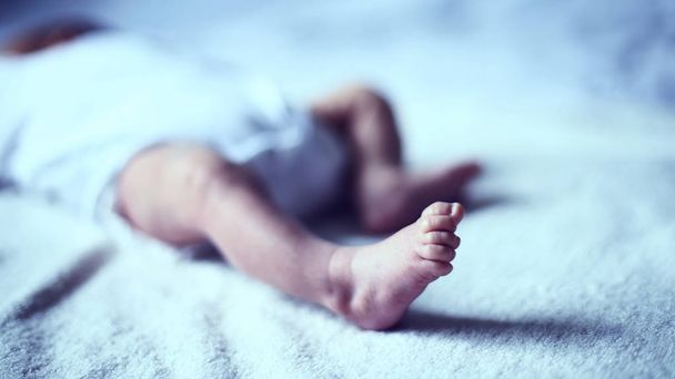 foot of a newborn who is sleeping peacefully in the crib - Фото, изображение