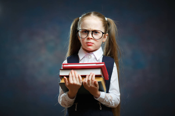 Serious Schoolgirl Wear Glasses Hold Pile of Book. Adorable Smart Elementary School Student in Big Spectacle. Clever Little Caucasian Girl. Kid Ready to Study Look at Camera - 写真・画像