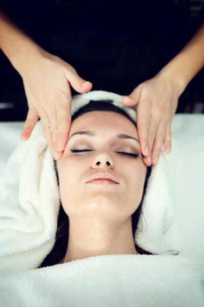 Closeup gezicht van jonge vrouw met gezichts massage in spa. - Foto, afbeelding