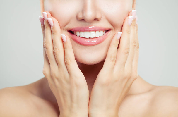 Крупный план женская улыбка и ухоженная рука. Французский маникюр, белые зубы и розовый глянец для губ
 - Фото, изображение