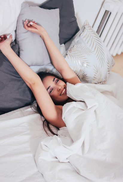 feliz sorrindo bonito longo cabelo asiático menina jovem mulher deitado no cama, aconchegante manhã
 - Foto, Imagem