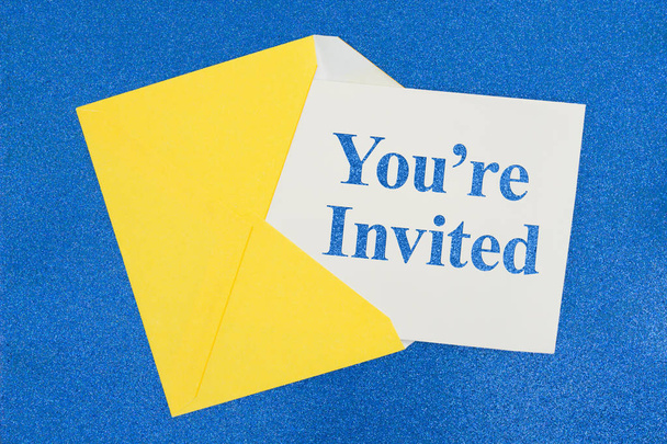 Είστε προσκληθεί μήνυμα σε λευκή κάρτα με ένα κίτρινο φάκελο σε χαρτί μπλε λάμψη - Φωτογραφία, εικόνα