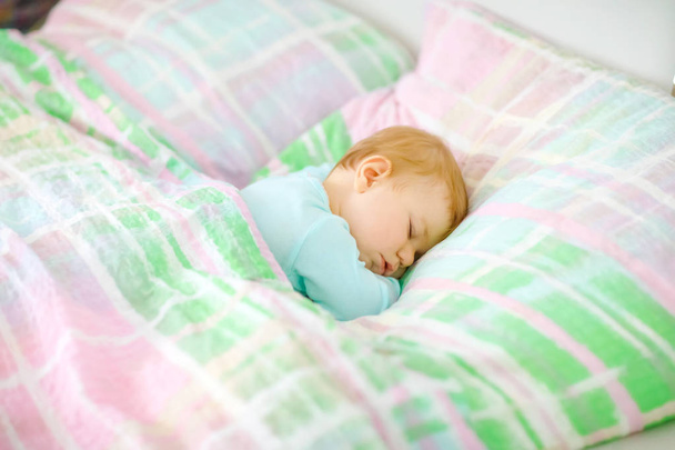 Adorable petite fille qui dort au lit. Calme enfant paisible rêvant pendant le sommeil de jour. Beau bébé dans le lit des parents. Dormir ensemble concept. - Photo, image