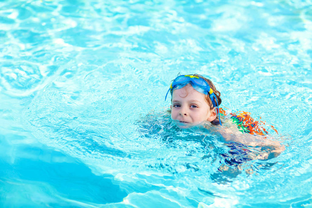 little preschool kid boy making swim competition sport. Kid with swimming goggles reaching edge of the pool . Child having fun in an swimming pool. Active happy child winning. sports, active leisure. - Photo, Image