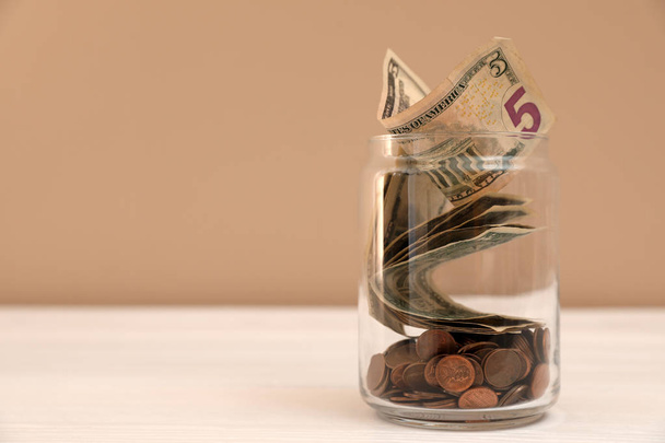 Donation jar with money on table against color background. Space for text - Photo, Image