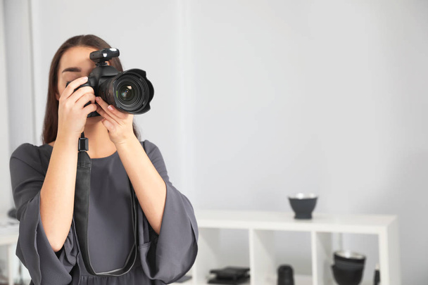 Young woman with professional camera in photo studio. Space for text - Foto, afbeelding