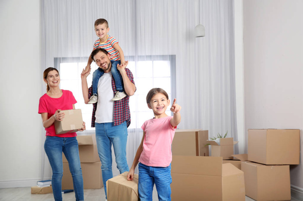 Happy family with moving boxes in their new house - Φωτογραφία, εικόνα