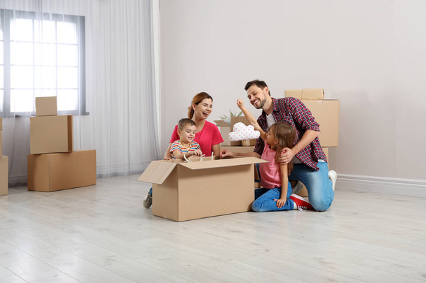 Family unpacking cardboard box in their new house. Moving day - Foto, Imagen