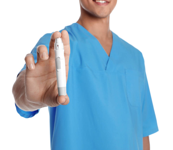 Male doctor holding lancet pen on white background, closeup. Medical object - Foto, Imagen