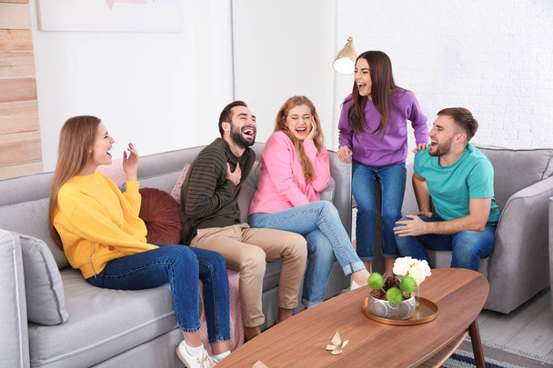 Group of friends telling jokes and laughing in living room - Fotó, kép