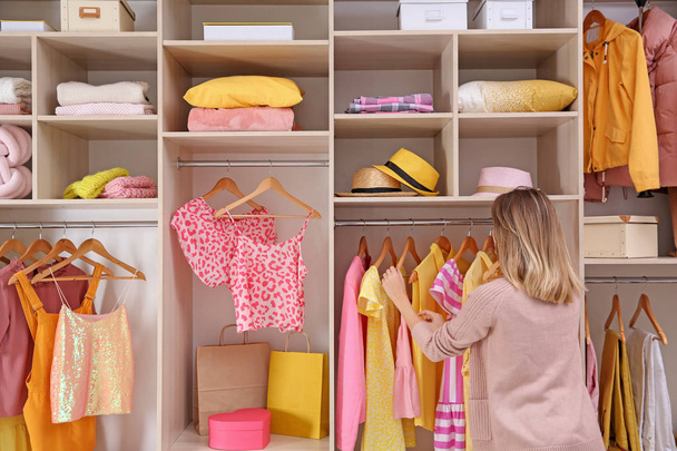 Woman choosing clothes from large wardrobe closet - Foto, afbeelding