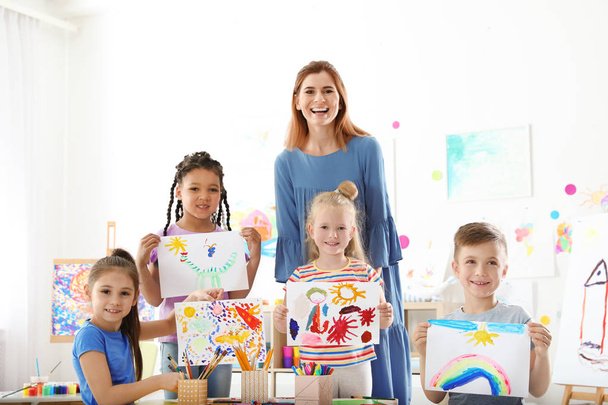 Cute little children with teacher showing their paintings at lesson indoors - Foto, immagini