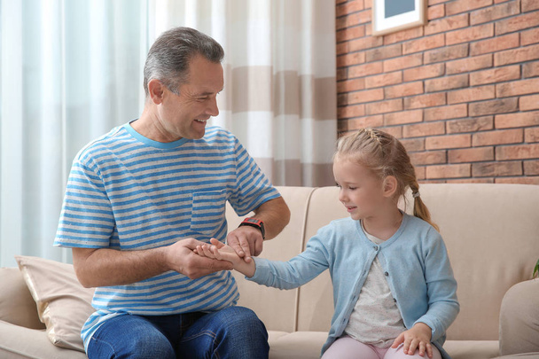 Mature man checking little girl's pulse with fingers at home - Fotografie, Obrázek