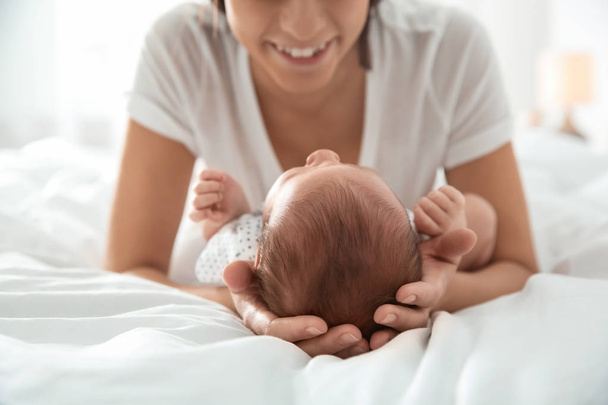 Young woman with her newborn baby on bed, closeup - Foto, imagen