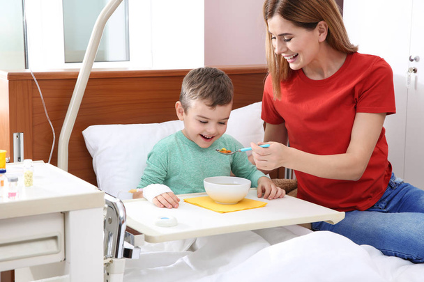 Woman feeding her little child with soup in hospital - Zdjęcie, obraz