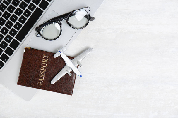 Flat lay composition with passport, laptop, toy plane and space for text on light background. Travel agency - Φωτογραφία, εικόνα