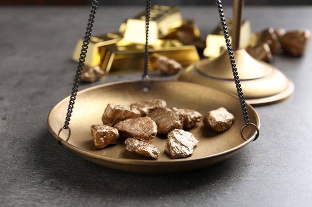 Scale pan with gold lumps on grey table, closeup - Foto, Bild