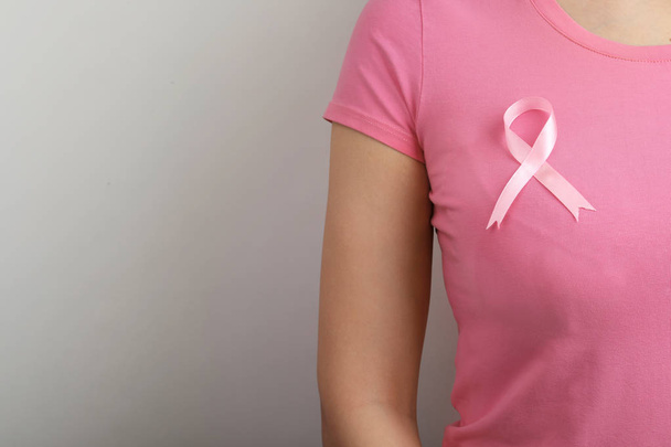 Woman with pink ribbon on grey background, space for text. Breast cancer awareness - Photo, image