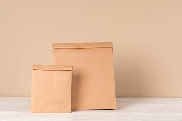 Paper bags on table against color background. Mockup for design - Foto, Imagen