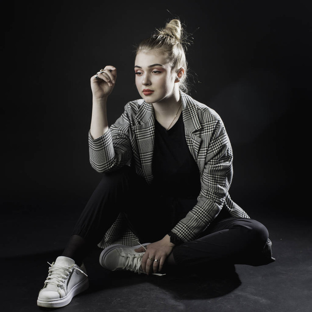 young girl in a gray jacket on a dark background in the studio s - Фото, изображение