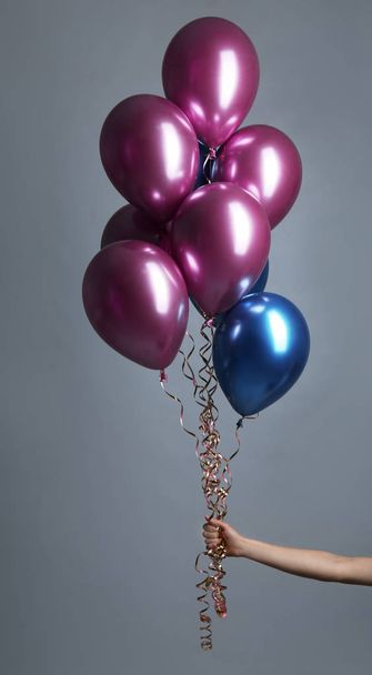 Woman holding bunch of balloons on grey background, closeup - Foto, imagen