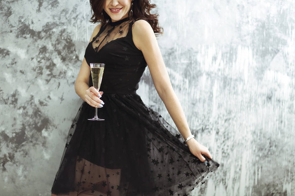 Smiling woman in black dress with a glass of champagne. Close up. Party concept - 写真・画像