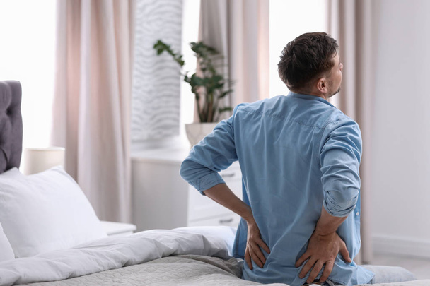 Young man suffering from back pain at home - Foto, Bild
