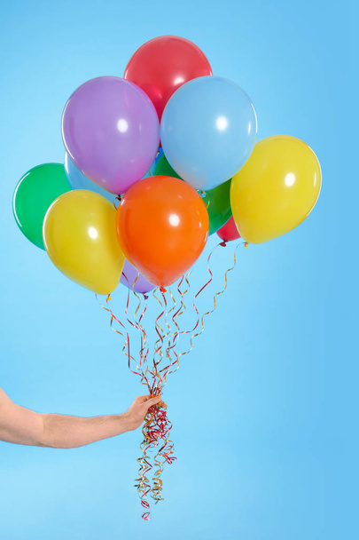 Man holding bunch of balloons on color background, closeup - Foto, Imagen