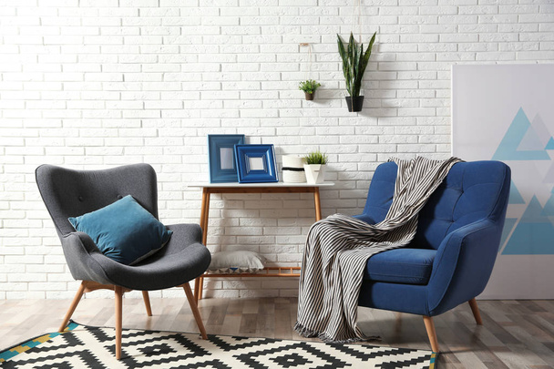 Modern interior with cozy armchairs and table near brick wall - Photo, image