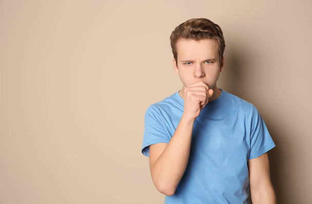 Teenage boy suffering from cough on color background. Space for text - Foto, imagen