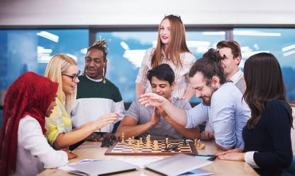 a multiethnic group of business people playing chess while having a break in modern startup office - Foto, Bild