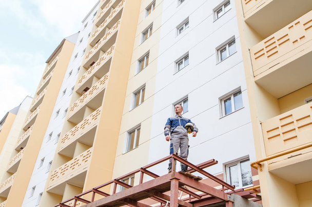 builder in shape on the background of a new building and sky - 写真・画像