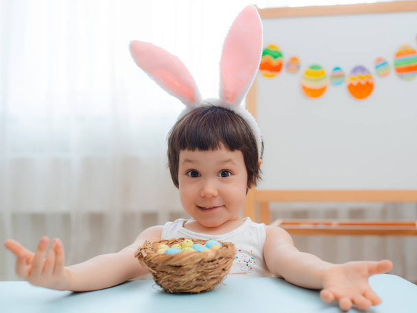 Dziewczynka w uszy królika są gry z pisanki. Dzieci z okazji Wielkanocy. Dzieci na Easter egg hunt. Dekoracji wnętrz, pastelowych bunny transparent. - Zdjęcie, obraz